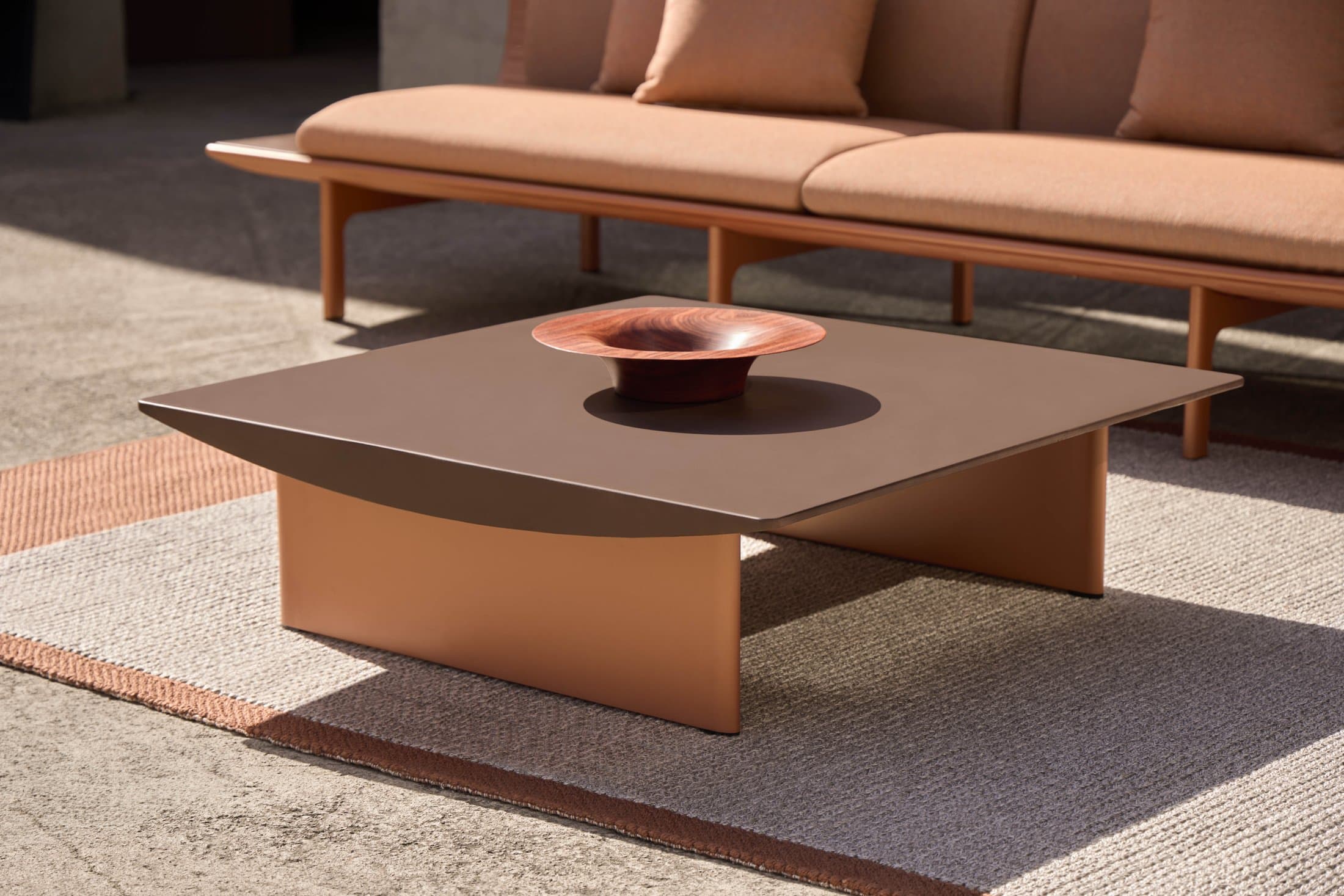 Dunne coffee table in cuprum with a 3-seat sofa behind.