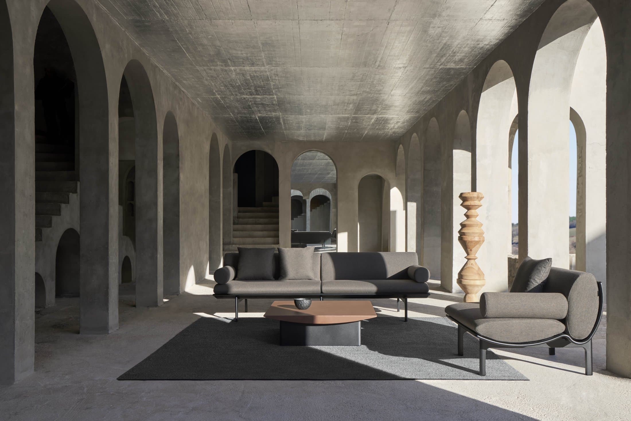 Dunne composition in black under a vaulted stone hall.