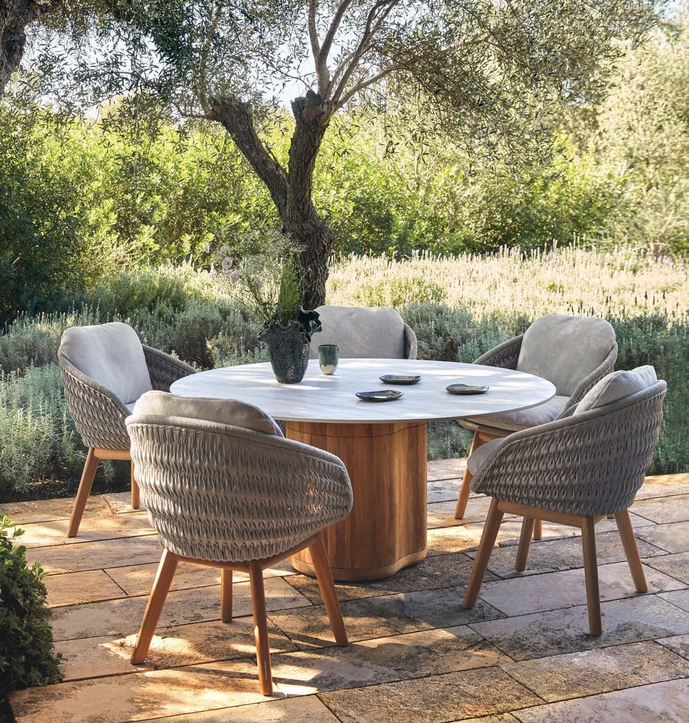 Manutti Ogado round teak table under an olive tree.