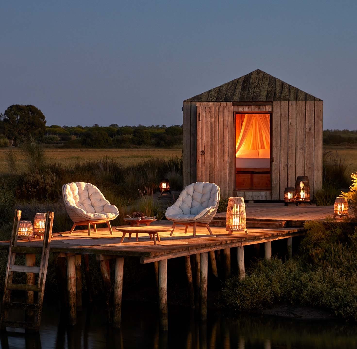 Manutti Sandua lanterns glowing on a lakeside jetty at dusk.